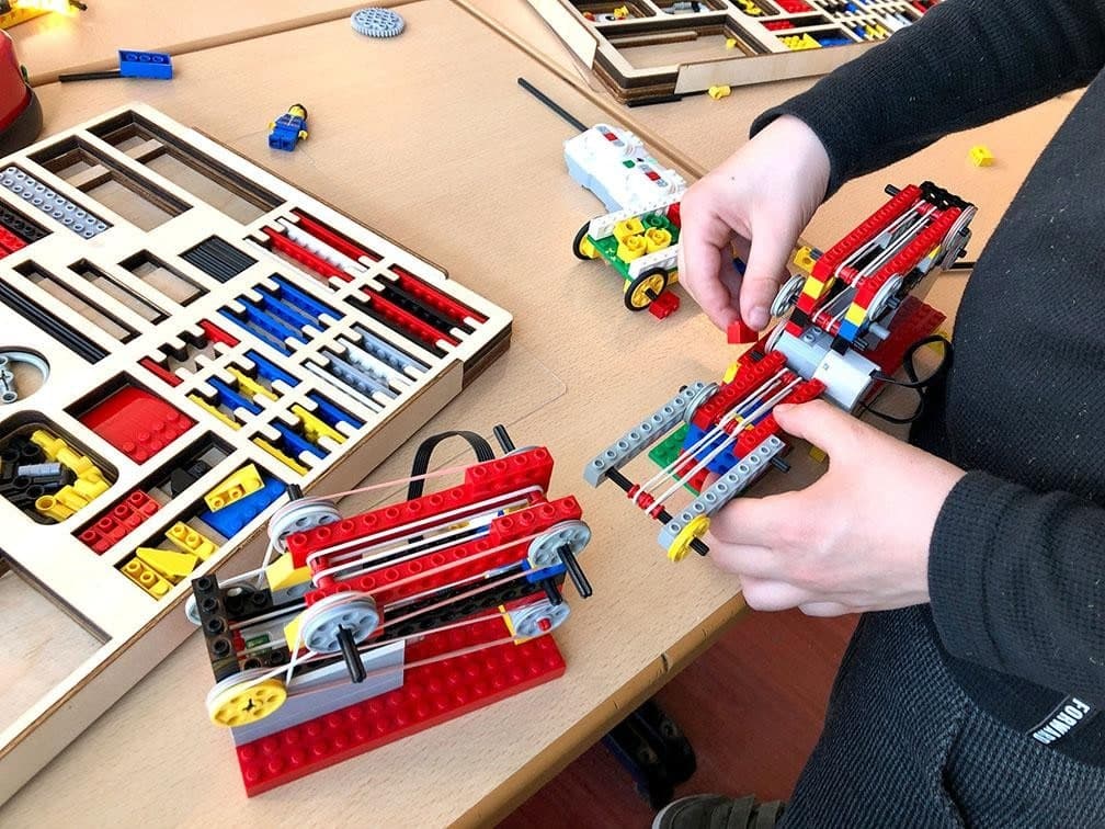 Een leerling bouwt een overbrenging met elastiekjes en tandwielen
